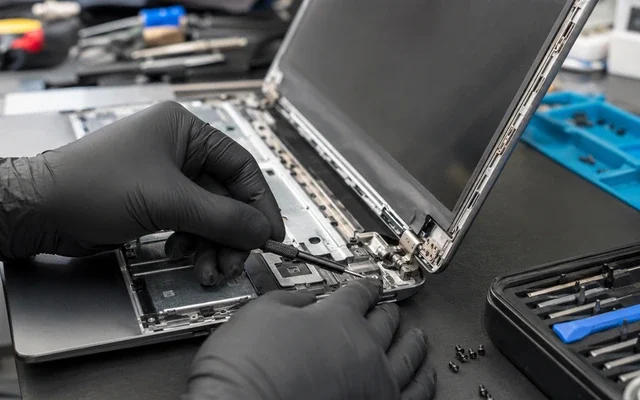 Laptop kasa ve menteşe tamiri yapan teknisyenin açık laptop üzerinde çalıştığını gösteren görsel